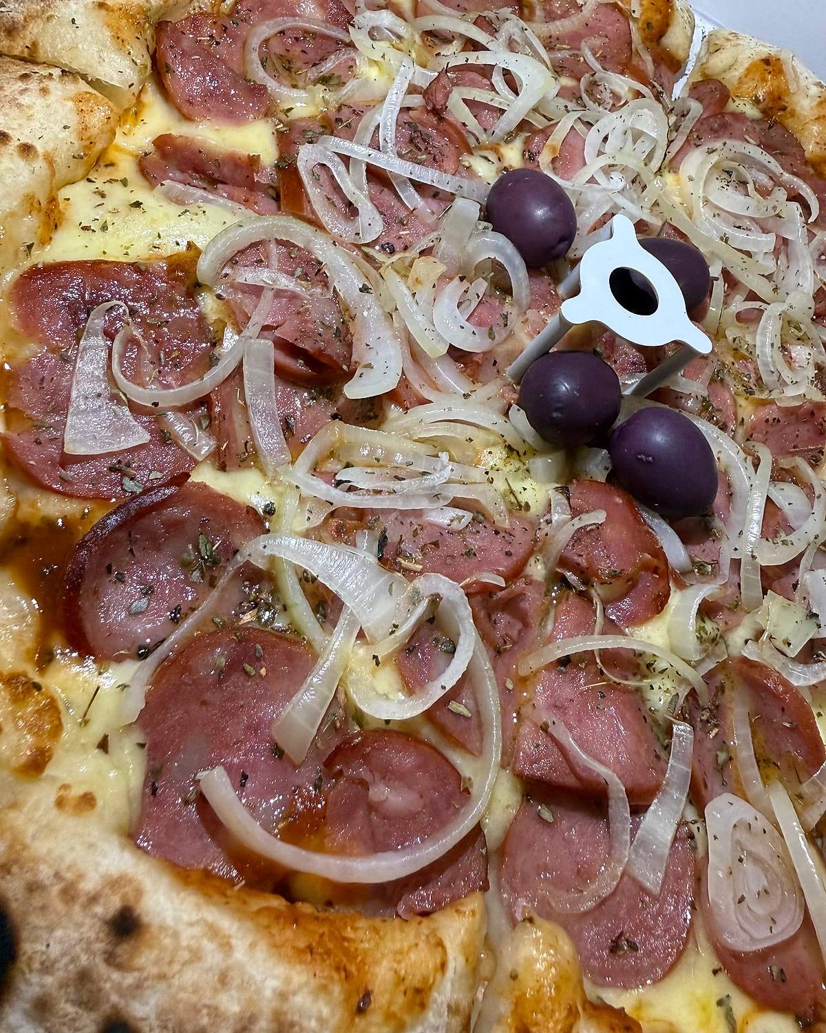 Pizza de calabresa com cebola e azeitonas roxas, borda alta e tostada