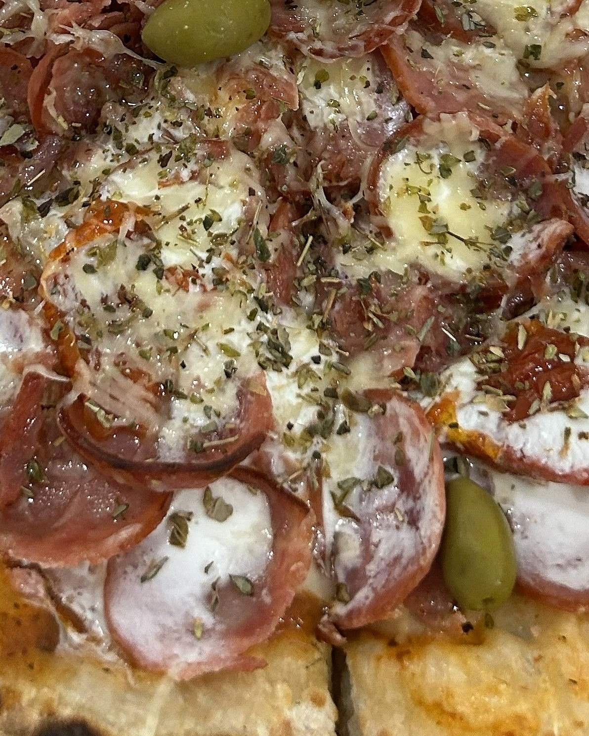 Pizza La Fratelli coberta de salame, calabresa, tomate seco e creme de leite, com a borda tostada