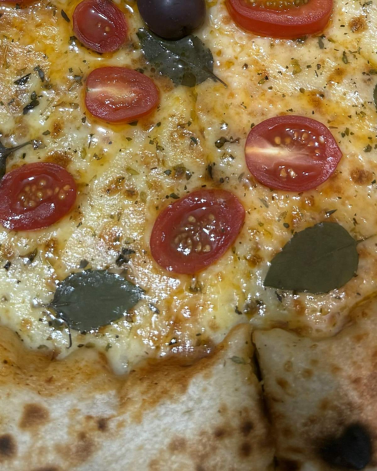 Pizza margherita com tomate cereja, manjericão e borda alta com marcas do forno