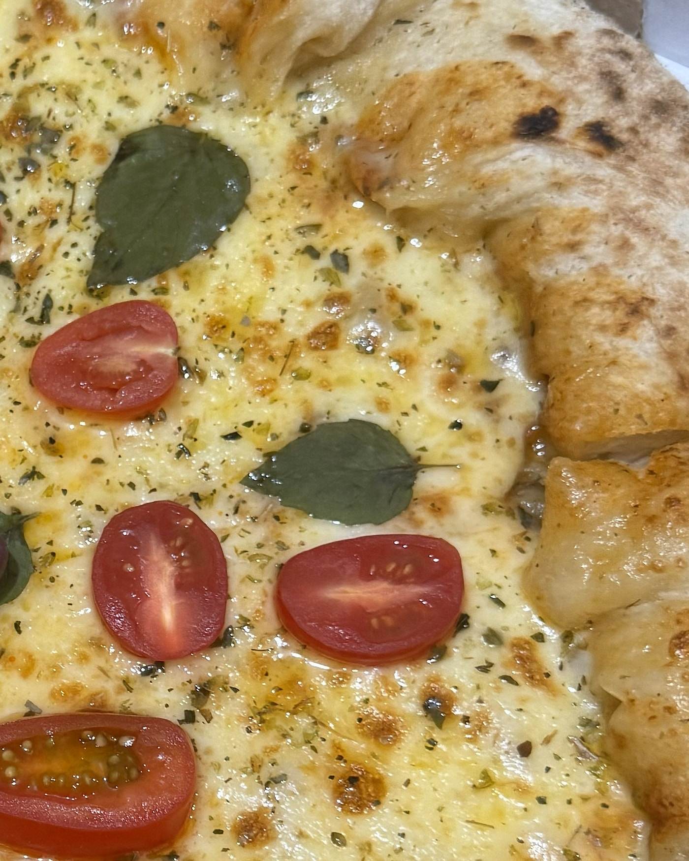 Detalhe da borda de uma pizza da La Fratelli: alta, dourada e com as marcas do forno